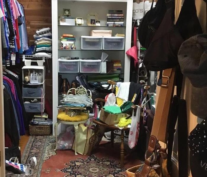 Closet full of clothes, purses, shoes, and a rug in front of a shelf
