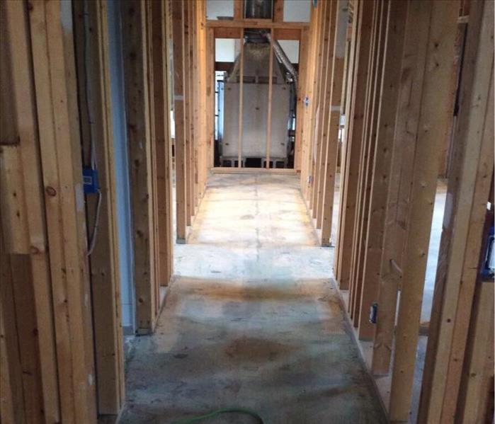 Completely gutted hallway with a cord on the floor